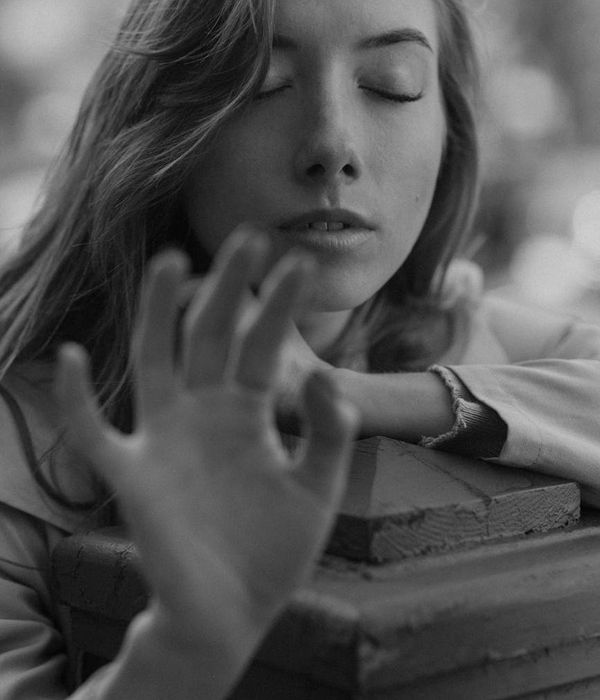 Woman in a calm yoga pose in a dark studio with teal light accents.